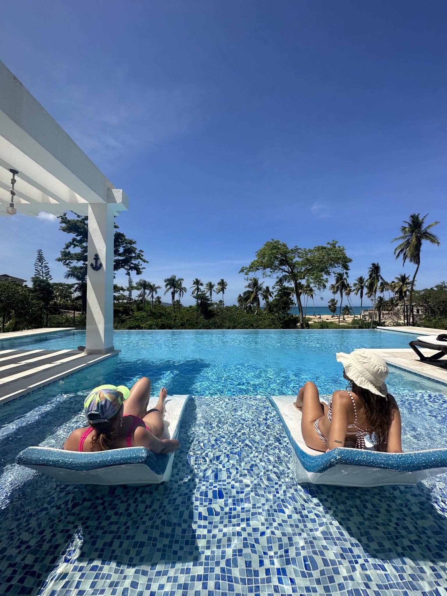 Guests relaxing in a villa infinity pool with a view of the sea, Dominican Republic